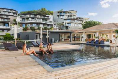 Guests relaxing by the dark-tiled communal pool on a wooden deck at Tamarind Hills resort, steps from the beach.
