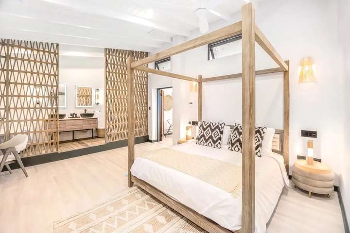 Ocean 19's luxurious master suite featuring a wooden four-poster king bed and an elegant open-plan bathroom with twin vanity.