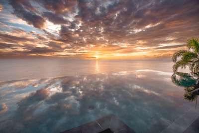 Ocean One's spectacular 56-foot infinity pool reflecting a vibrant Caribbean sunset, offering the ultimate luxury escape.