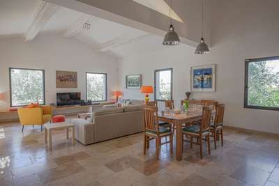 Open-plan living and dining space showcasing vaulted ceilings, exposed beams, and elegant stone flooring.