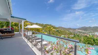 Luxury St-Barths villa terrace featuring a heated infinity pool and panoramic ocean views of St-Jean Bay.