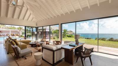 Grand living room with striking white vaulted ceilings, contemporary luxury furnishings, and expansive ocean view bay windows.