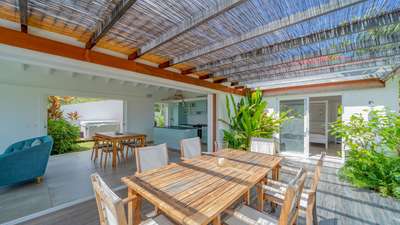 Elegant outdoor dining terrace leading into a fully-equipped kitchen with a central island at luxury St-Barths villa.