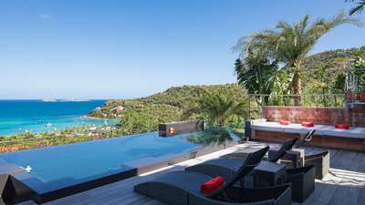 Elegant sun loungers and a comfortable daybed beside the heated infinity pool, offering stunning Caribbean ocean views.