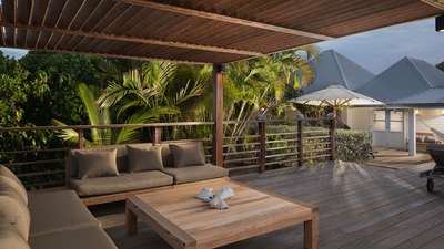 Elegant outdoor lounge sheltered by a graceful wooden pergola on the rich teak terrace at Villa Pastels by night.