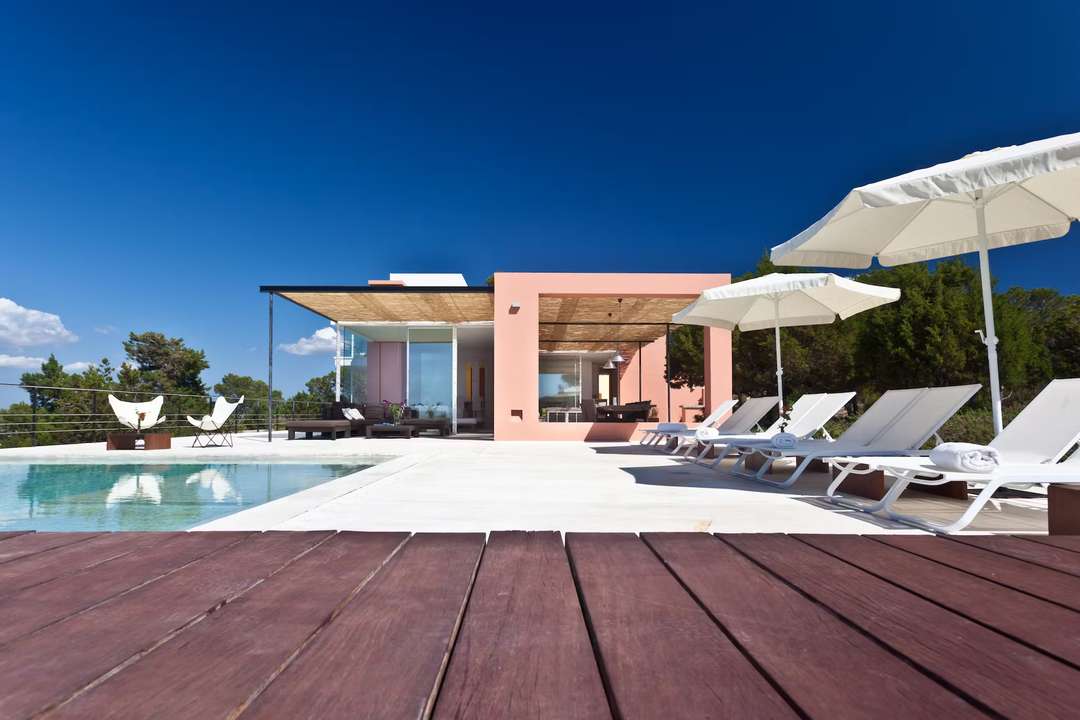 Expansive infinity pool and sun-drenched terrace with white loungers at Villa Pep Calo, offering a luxurious Ibiza escape.