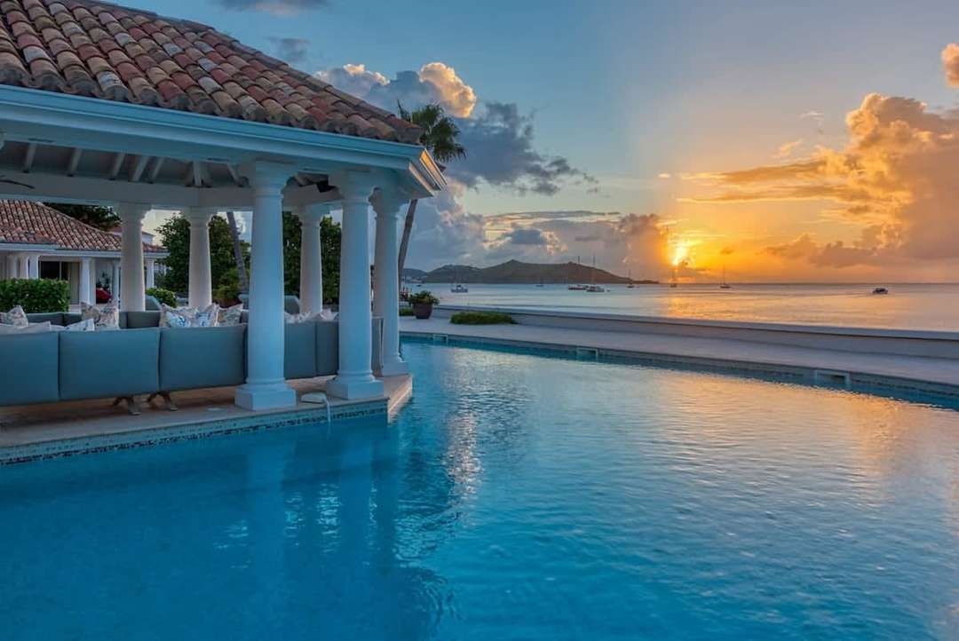 Breathtaking sunset views over the Caribbean Sea from the heated infinity pool and covered loggia at Petite Plage 5 villa.