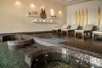 Elegant indoor wellness spa at Poggio Prezioso featuring a mosaic-tiled heated pool, wooden decking, and plush sun loungers.