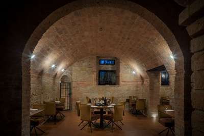Dine in the historic vaulted brick cellar at Poggio Prezioso, featuring an elegant on-site restaurant with velvet seating.