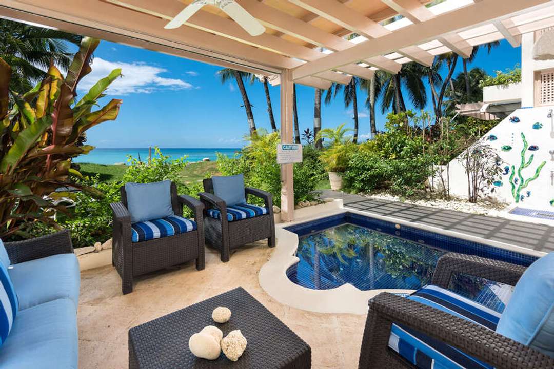 Ground-floor covered terrace with a private plunge pool, lounge seating, and direct beach access at Reeds House 4.