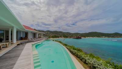 Superb heated infinity pool and wooden terrace at Villa Reef Point, framing panoramic views of St. Jean Bay's azure waters.