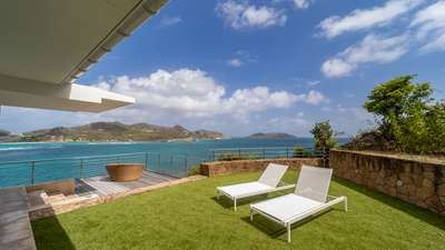 Private sun-drenched terrace with chic loungers overlooking the turquoise waters of St. Jean Bay for ultimate relaxation.