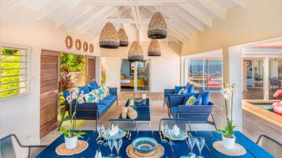 Sophisticated outdoor living and dining area with blue furnishings, woven pendants, and pool views at Villa Roy in Vitet.