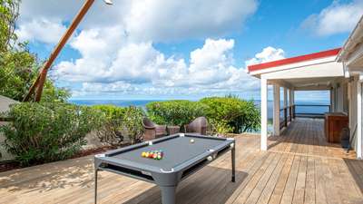 Luxury outdoor wooden deck featuring a unique pool table, comfortable seating, and breathtaking ocean views in Vitet.