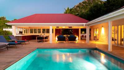 Beautifully illuminated private pool and wooden deck at night, showcasing the villa's elegant covered outdoor lounge area.