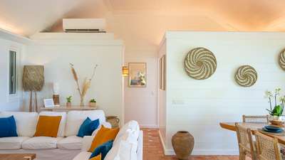 Tranquil St. Barts villa living space with creamy white interiors, terracotta floors, plush seating, and woven wall decor.