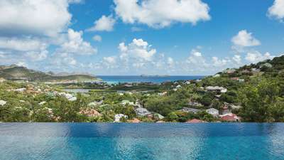 Stunning infinity pool edge seamlessly blending with breathtaking panoramic views of St-Jean Bay and lush tropical landscapes.