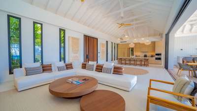 Sophisticated luxury villa living room with a white sectional, bleached parquet floors, and a light wood gourmet kitchen.