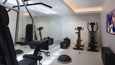 Fully equipped private fitness room at Villa Seala featuring modern machines, mirrored walls, and a TV.