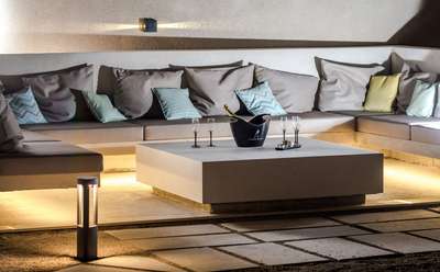 Elegant outdoor lounge area featuring built-in seating, plush cushions, and ambient night lighting for evening relaxation.
