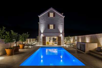 Illuminated private heated pool and elegant terrace at night, seamlessly connecting to the villa's stylish ground floor.