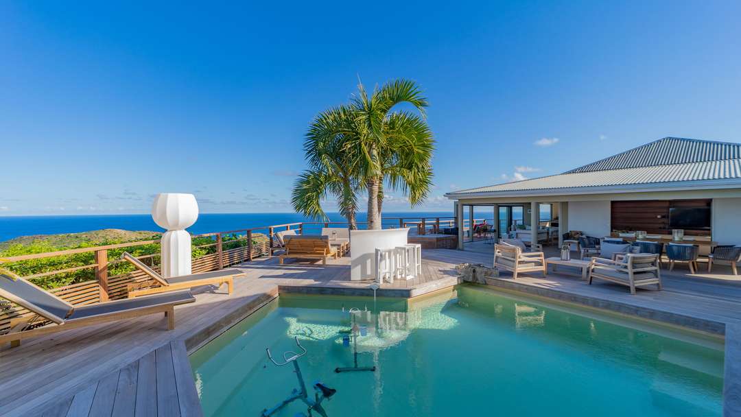 Heated pool with aquabikes and outdoor bar on the sun-drenched terrace of Villa Seastar, offering panoramic Caribbean views.