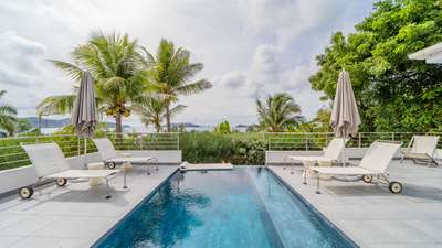 Spectacular infinity pool merging with the ocean horizon, flanked by white sun loungers on a spacious St-Barths terrace.