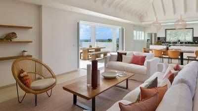 Elegant living room at South Wave with plush white sofas, wooden coffee table, and seamless access to the ocean-view terrace.