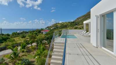Expansive sun terrace with a sparkling private pool, sleek loungers, and breathtaking ocean views at a luxury Toiny villa.