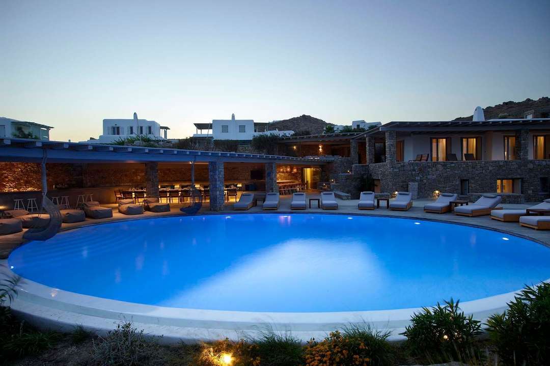 Elegant circular infinity pool at Villa Starfish at dusk, featuring a covered dining area and stunning stone architecture.