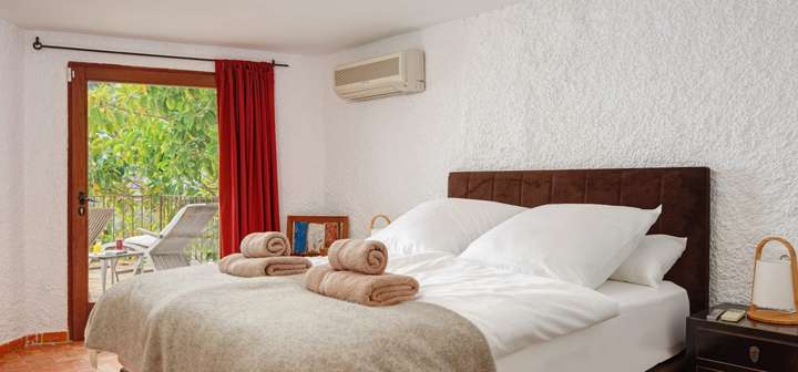 Luxury queen bedroom at Stone Whisper with a velvet headboard, crisp white linens, and direct access to a lush terrace.