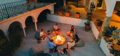 Friends gather around the outdoor fire pit at Stone Whisper villa, enjoying a relaxed evening in the private sandy courtyard.