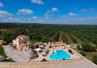Aerial view of Sublimia's luxury stone villa, heart-shaped pool, and expansive olive groves in the Puglia countryside.