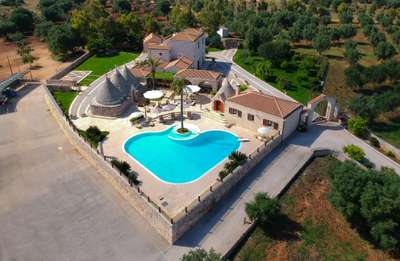 Stunning aerial view of Sublimia's heart-shaped pool, traditional stone trulli, and serene rural landscape in Puglia.