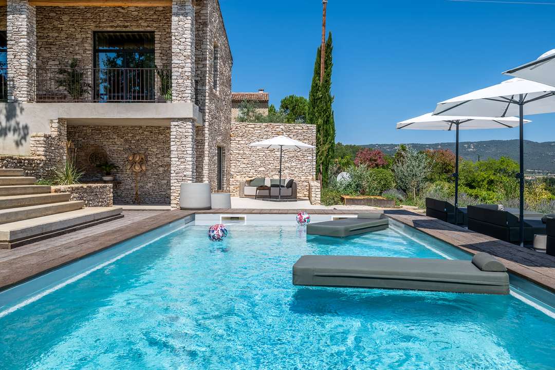 Heated pool with floating loungers at La Maison de Tara, featuring traditional Bories stone architecture and countryside views.