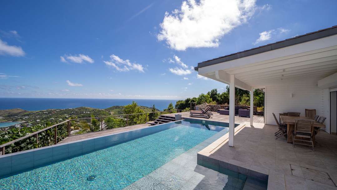 Private infinity pool and wooden sun deck at Villa Teddy, offering breathtaking panoramic ocean views over the Caribbean Sea.