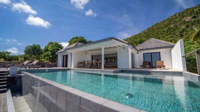 Elegant Villa Teddy exterior showcasing a private infinity pool, wooden sun deck with loungers, and covered dining space.