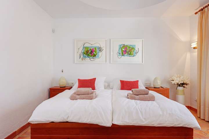 Elegant bedroom in our Villajoyosa villa featuring a plush double bed, terracotta floors, and vibrant modern art.