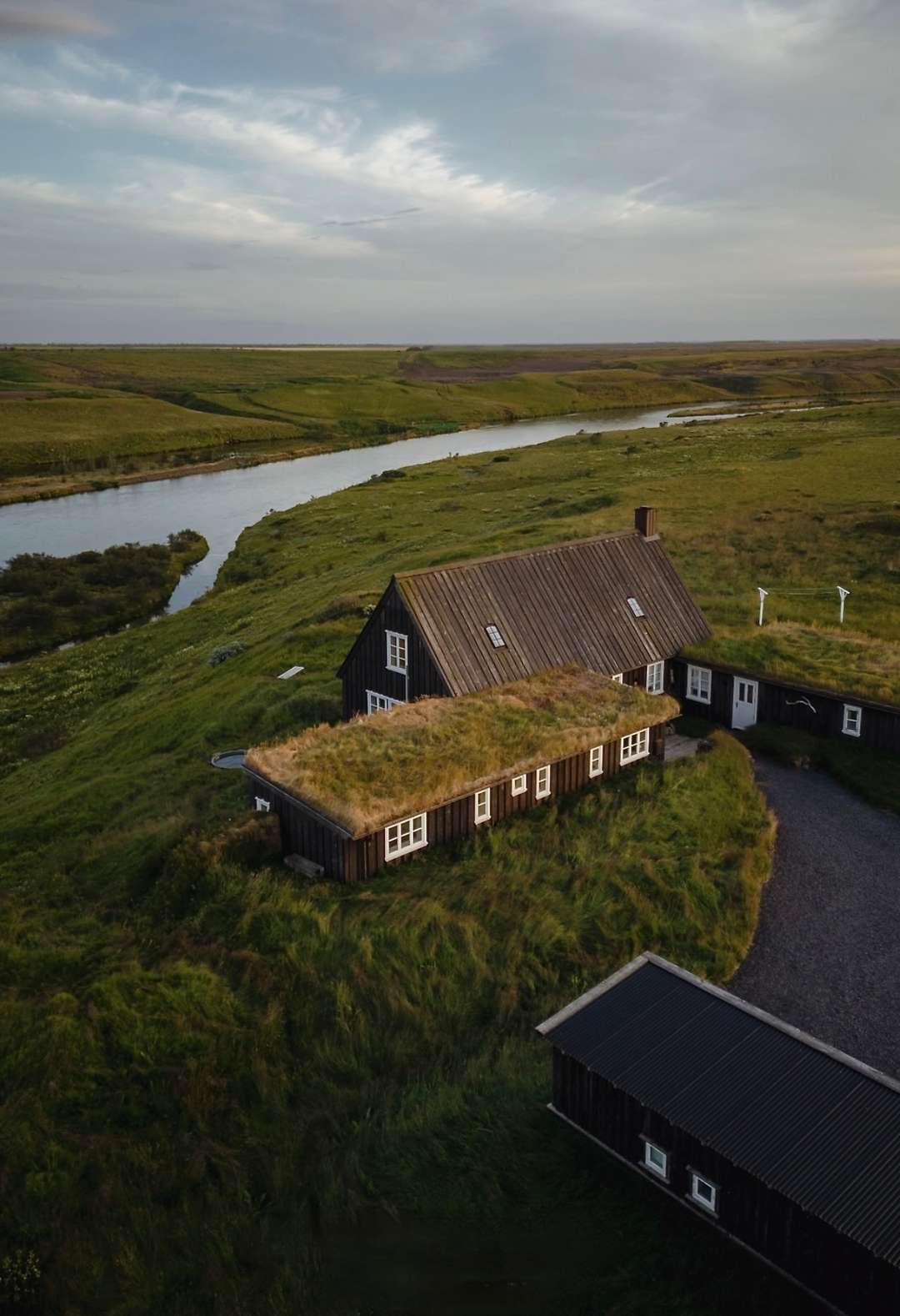 Aerial view of The River Lodge, a historic dark wood property with a grass roof set on the scenic banks of River Mói.