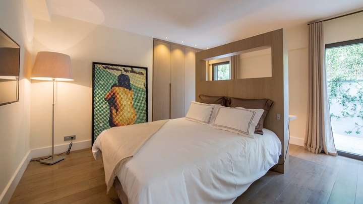Stylish double bedroom with pop art decor, custom wood headboard, and sliding glass doors leading to a cozy outdoor patio.