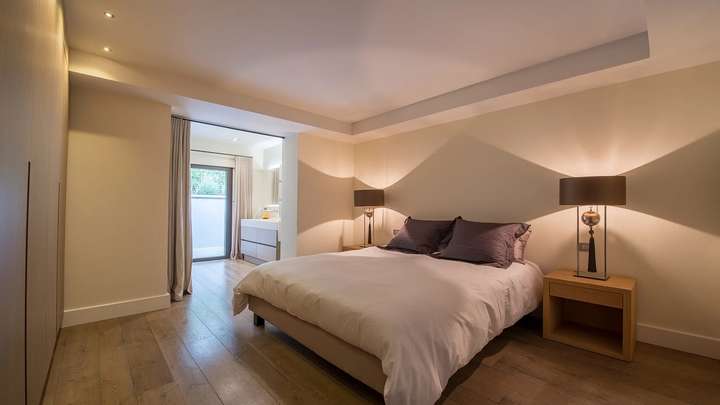 Serene double bedroom with plush bedding, elegant bedside lighting, and seamless access to a modern ensuite bathroom.