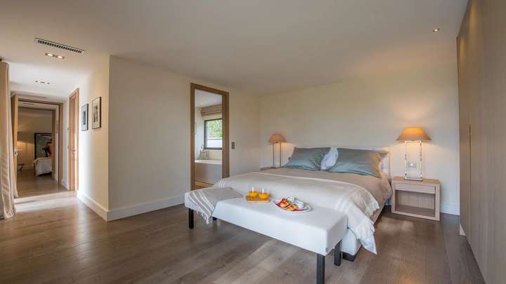 Spacious luxury bedroom featuring hardwood floors, elegant decor, and a relaxing breakfast setup in a St Tropez townhouse.