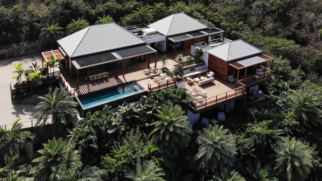 Aerial view of Villa Thelma in Marigot, showcasing modern architecture, wooden decks, an infinity pool, and lush surroundings.
