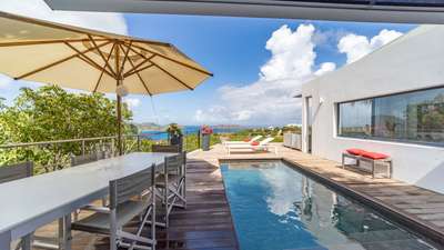 Sprawling wooden terrace with a private pool and shaded alfresco dining area overlooking the azure Caribbean Sea.