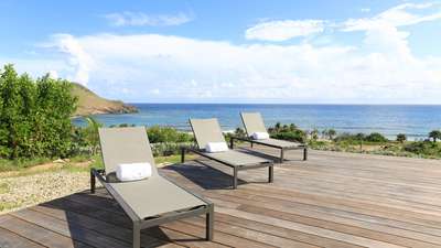 Elegant sun loungers on a spacious wooden deck, offering breathtaking panoramic ocean views at this luxury St. Barths villa.