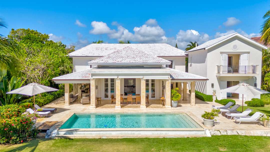 Elegant Punta Cana villa exterior featuring a marble-framed private pool, sun loungers, and a spacious covered verandah.