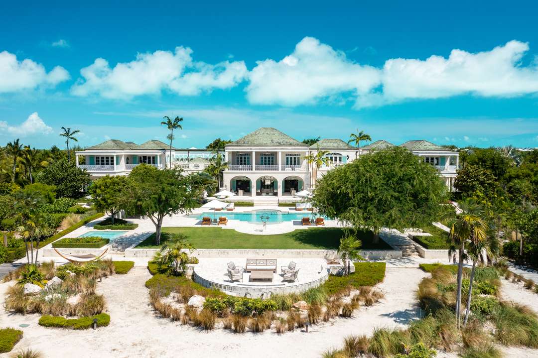 Aerial view of Tranquility villa's grand estate, featuring a large pool, lush gardens, and elegant colonial architecture.