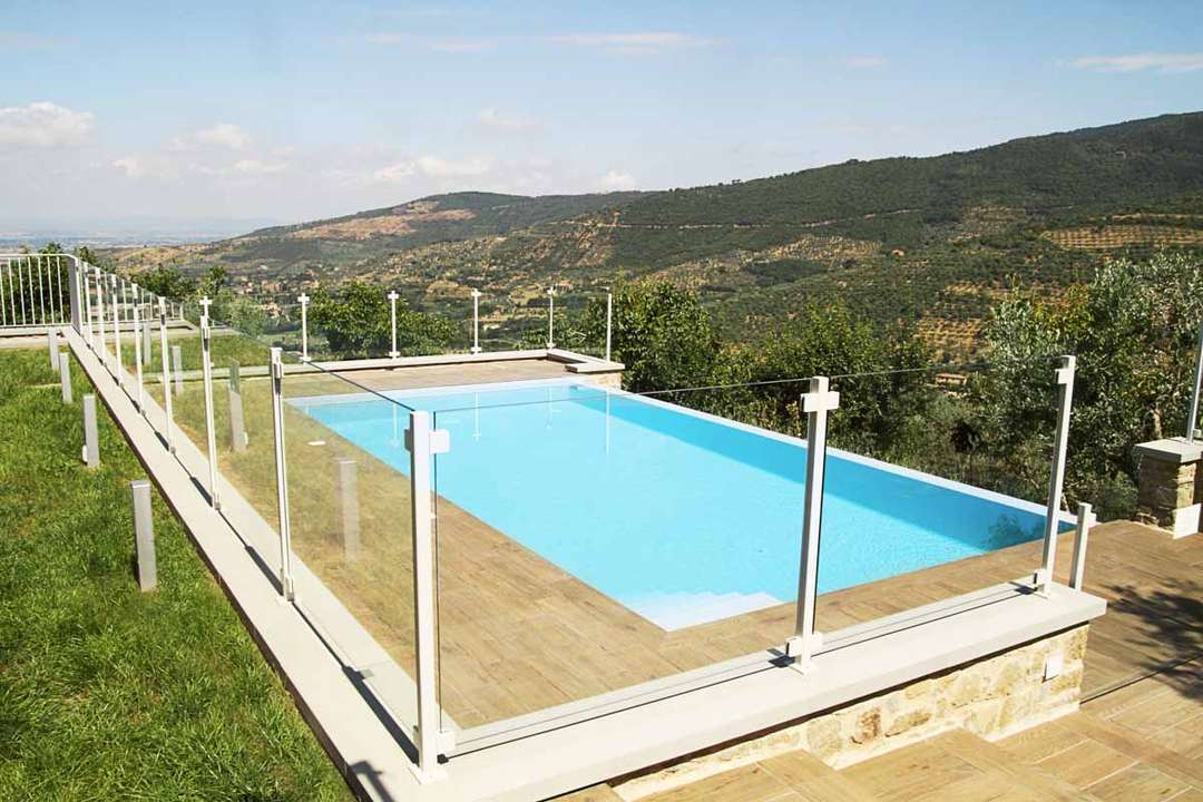 Private infinity-edge swimming pool with glass railings offering breathtaking views of the Tuscan countryside at Villa Tullia.