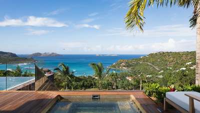 Luxurious mosaic-tiled jacuzzi nestled on a wooden deck amidst tropical palms with breathtaking Caribbean Sea views.