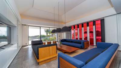 Sophisticated living room in St. Barth with plush blue sofas, noble wood accents, and expansive windows framing ocean views.